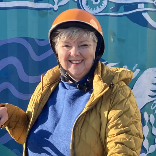 Profile picture of Helen, smiling and wearing a helmet